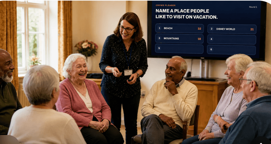 Older adults gathered in a semicircle with an engaged facilitator and a dark word-puzzle game displayed on the TV screen